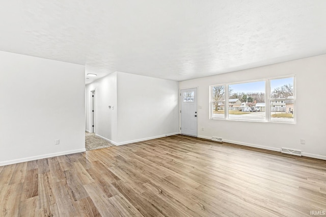 unfurnished living room featuring a textured ceiling and light hardwood / wood-style floors