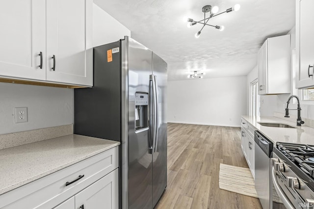 kitchen featuring stainless steel appliances, sink, white cabinets, and light hardwood / wood-style floors