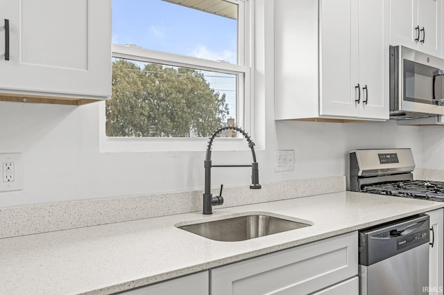 kitchen featuring light stone countertops, white cabinetry, appliances with stainless steel finishes, and sink