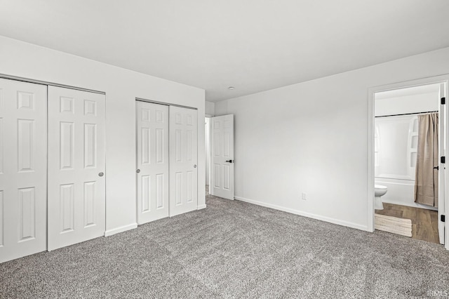 unfurnished bedroom featuring connected bathroom, carpet flooring, and two closets