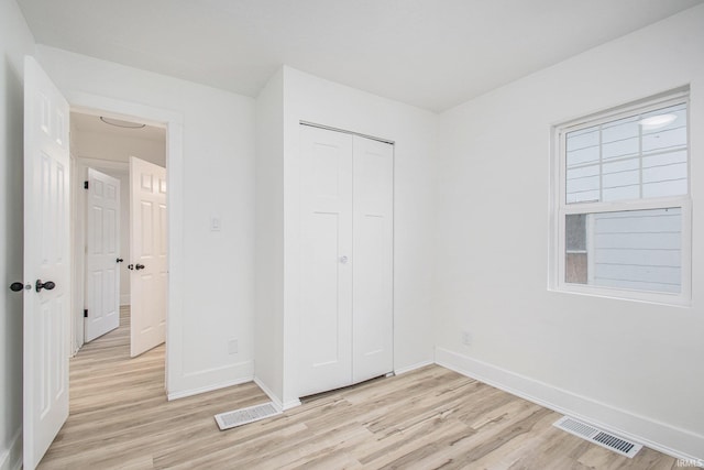 unfurnished bedroom with light wood-type flooring and a closet