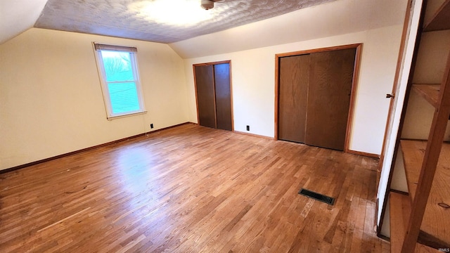 bonus room with vaulted ceiling, a textured ceiling, and light wood-type flooring