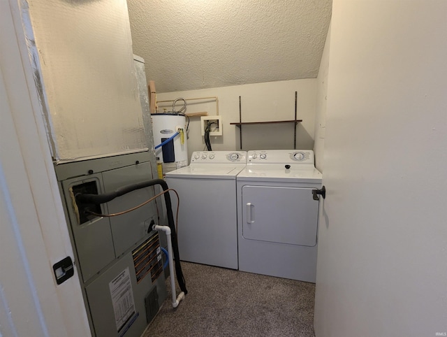 laundry area with water heater, washing machine and dryer, and a textured ceiling