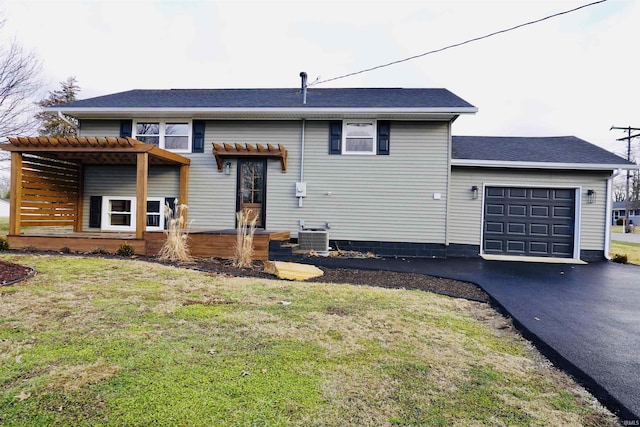 view of front of home featuring a garage, cooling unit, and a front lawn