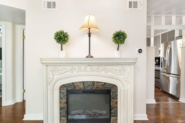 interior details with appliances with stainless steel finishes, hardwood / wood-style floors, and a tile fireplace