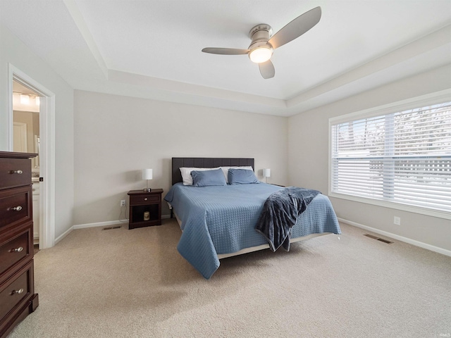 carpeted bedroom with ceiling fan and a tray ceiling