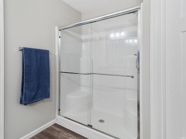 bathroom with a shower with door and hardwood / wood-style floors