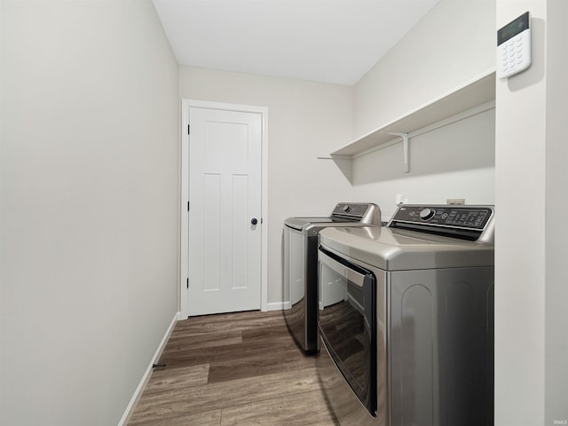 clothes washing area with washing machine and clothes dryer and wood-type flooring