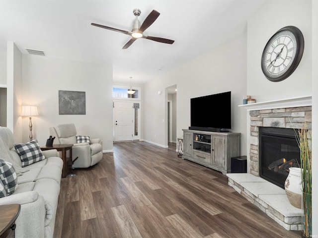 living room featuring ceiling fan, dark hardwood / wood-style floors, and a fireplace