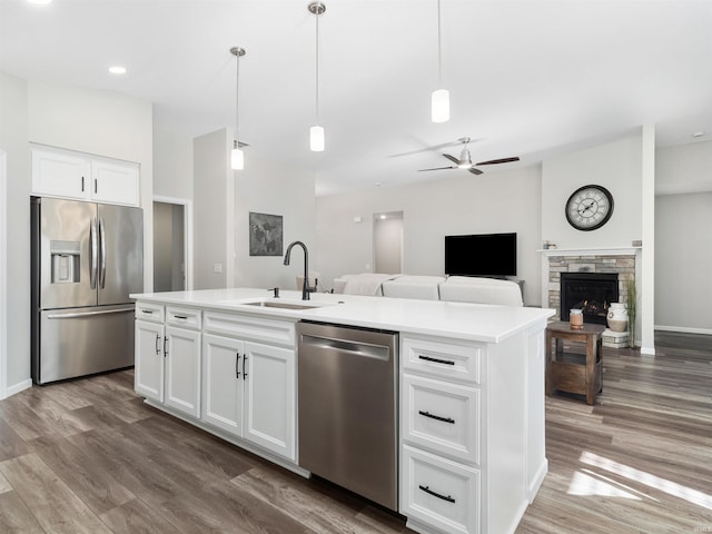 kitchen with decorative light fixtures, white cabinetry, sink, a kitchen island with sink, and stainless steel appliances