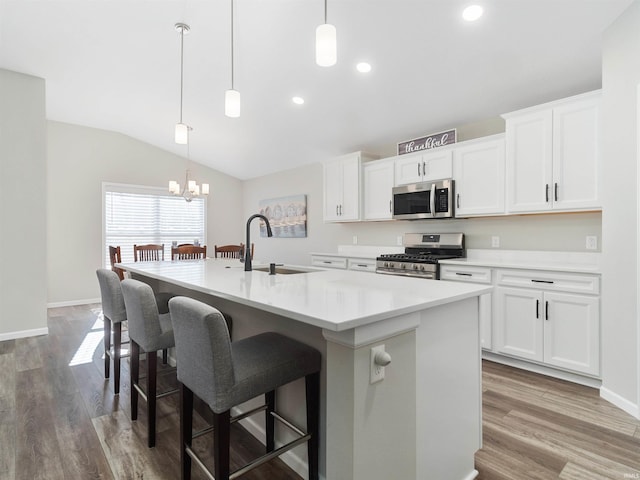 kitchen with sink, pendant lighting, stainless steel appliances, a kitchen island with sink, and white cabinets