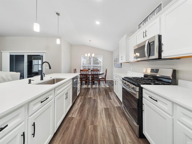 kitchen featuring dark wood-type flooring, sink, white cabinetry, hanging light fixtures, and appliances with stainless steel finishes