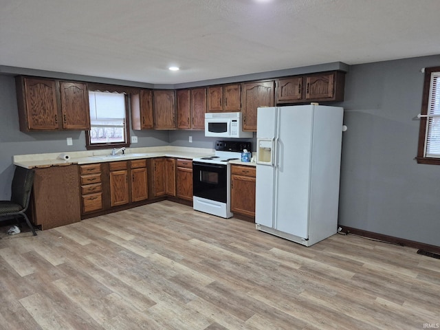 kitchen featuring white appliances, light hardwood / wood-style floors, and sink