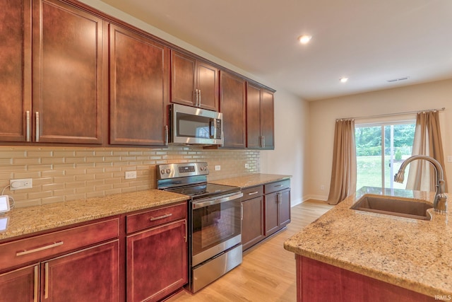 kitchen featuring sink, backsplash, stainless steel appliances, and light stone countertops
