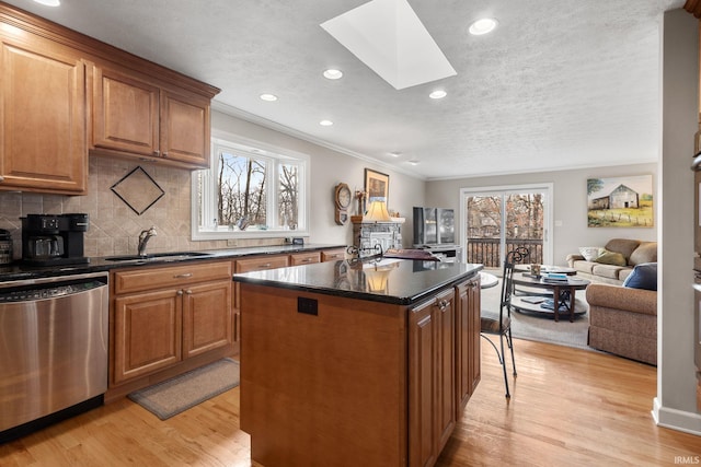 kitchen with a skylight, sink, a center island, stainless steel dishwasher, and light hardwood / wood-style floors