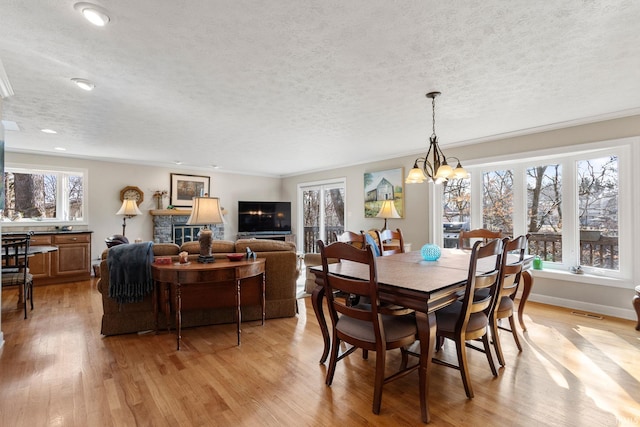 dining space with crown molding, light hardwood / wood-style floors, a chandelier, and a textured ceiling