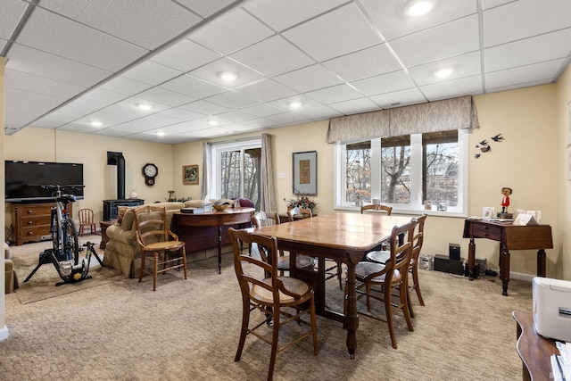 carpeted dining room with a wood stove and a paneled ceiling