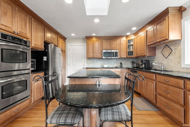 kitchen with dark stone countertops, a breakfast bar, appliances with stainless steel finishes, and a kitchen island