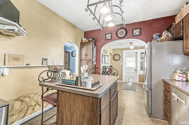 kitchen featuring a kitchen island, appliances with stainless steel finishes, a kitchen bar, and ceiling fan