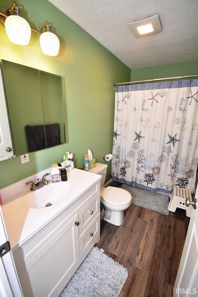 bathroom featuring vanity, toilet, hardwood / wood-style floors, and a textured ceiling