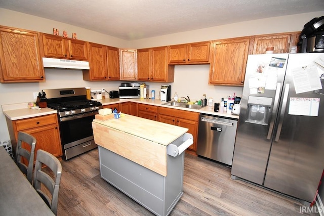 kitchen with stainless steel appliances, sink, and wood-type flooring