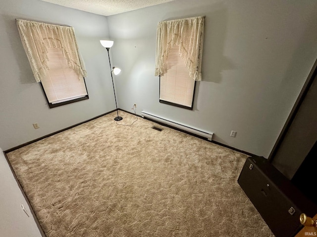 carpeted spare room featuring a baseboard heating unit and a textured ceiling