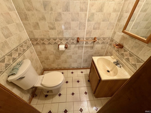 bathroom with toilet, tile patterned flooring, and tile walls