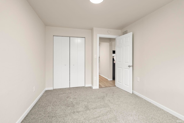 unfurnished bedroom with light colored carpet and a closet