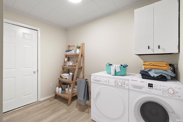 laundry room featuring cabinets, independent washer and dryer, and light hardwood / wood-style flooring