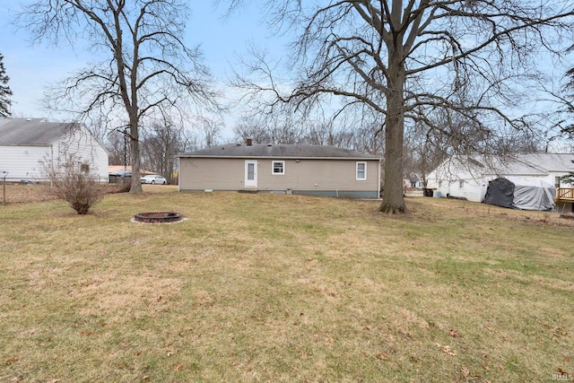 back of property with a lawn and a fire pit