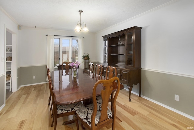 dining space featuring ornamental molding, light hardwood / wood-style floors, and a notable chandelier