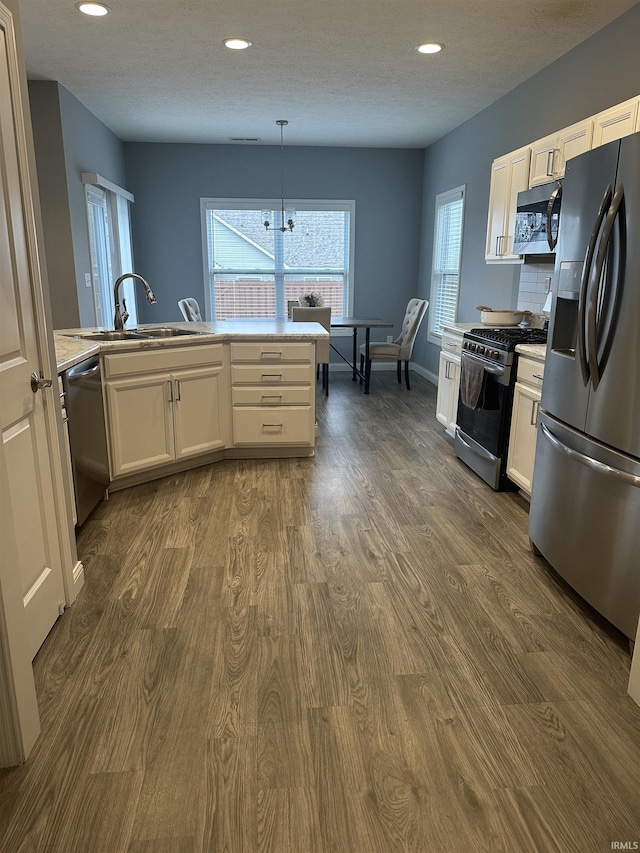 kitchen featuring dark hardwood / wood-style floors, decorative light fixtures, sink, white cabinets, and stainless steel appliances