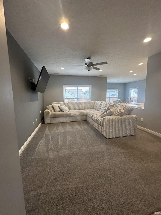 carpeted living room with ceiling fan and a textured ceiling