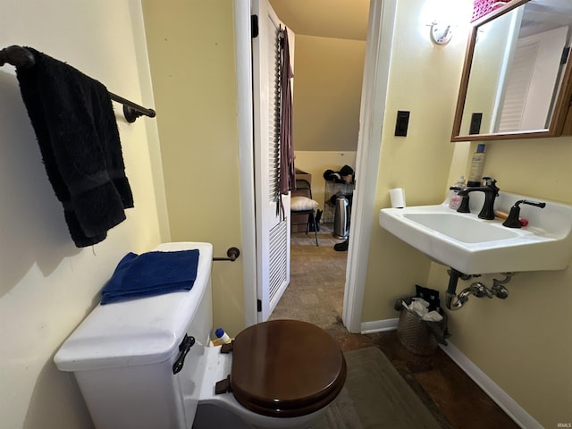 half bathroom with toilet, baseboards, and a sink