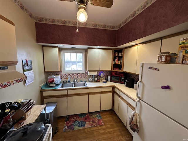 kitchen featuring wood finished floors, freestanding refrigerator, a sink, light countertops, and stove