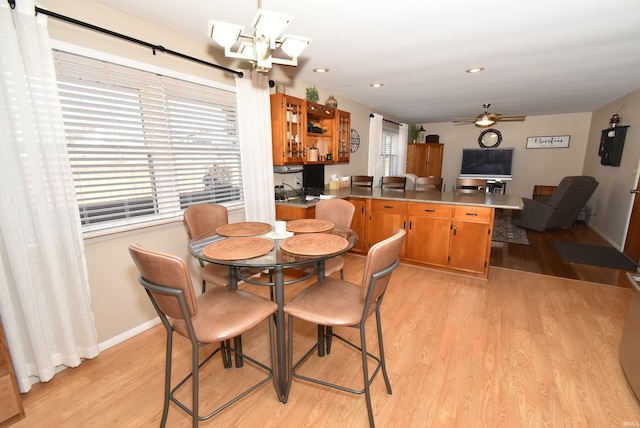 dining area with ceiling fan with notable chandelier and light wood-type flooring