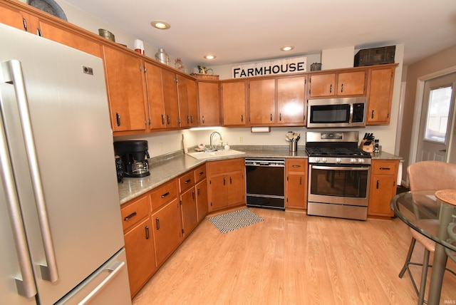 kitchen with stainless steel appliances, sink, and light hardwood / wood-style floors