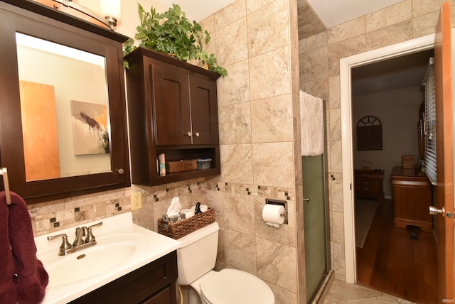 bathroom with tile walls, vanity, toilet, and walk in shower