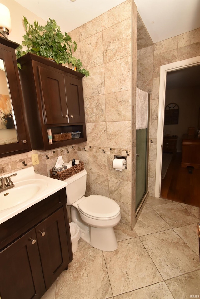 bathroom featuring tile patterned floors, toilet, an enclosed shower, tile walls, and vanity