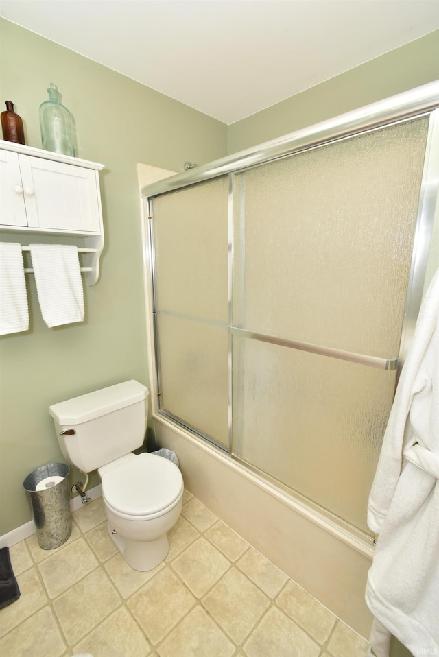 bathroom with toilet, tile patterned floors, and bath / shower combo with glass door