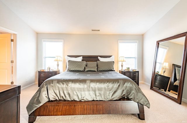 bedroom with light carpet and multiple windows