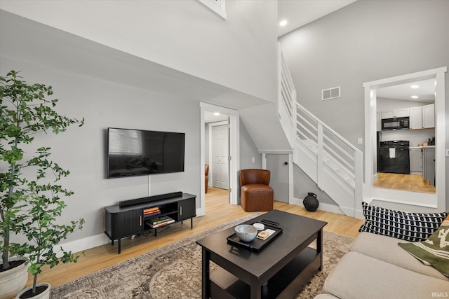 living room with a high ceiling and light wood-type flooring