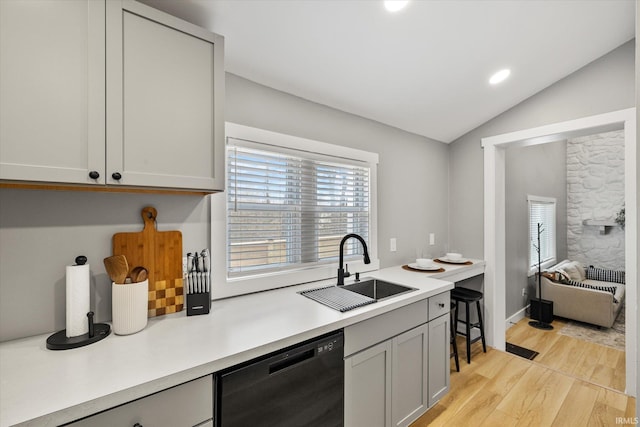 kitchen with gray cabinets, lofted ceiling, black dishwasher, sink, and light hardwood / wood-style flooring