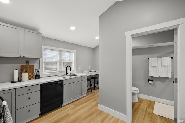 kitchen featuring lofted ceiling, sink, gray cabinetry, light hardwood / wood-style flooring, and dishwasher