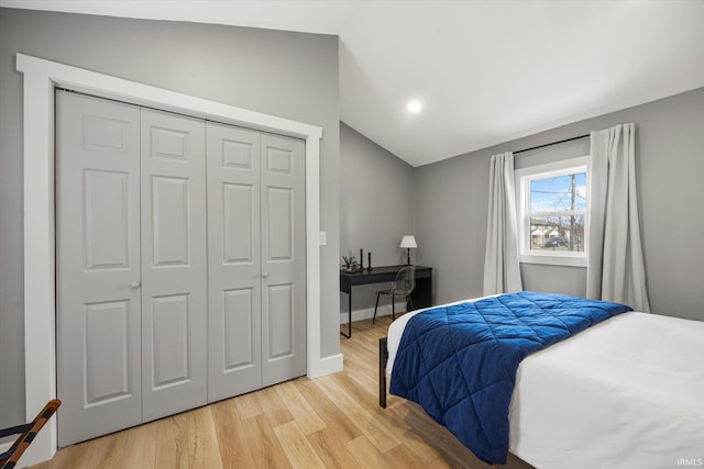 bedroom with lofted ceiling, a closet, and light wood-type flooring