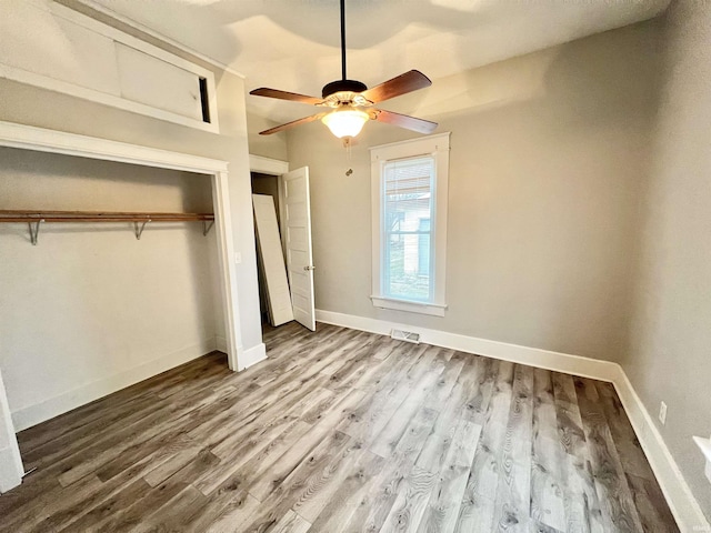 unfurnished bedroom with hardwood / wood-style floors, ceiling fan, and a closet