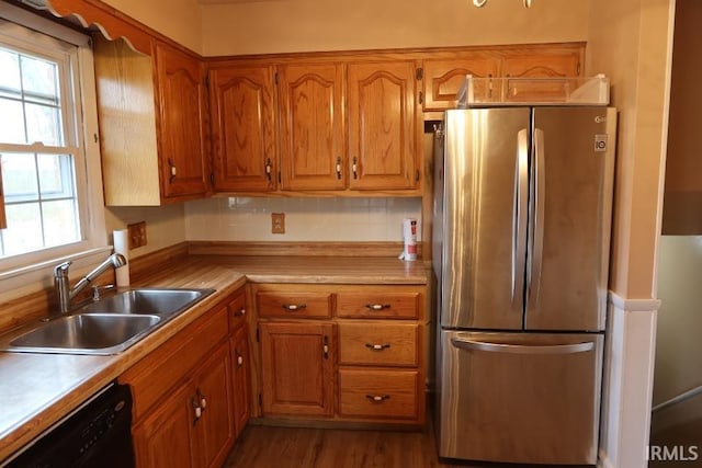 kitchen featuring black dishwasher, sink, dark wood-type flooring, and stainless steel fridge