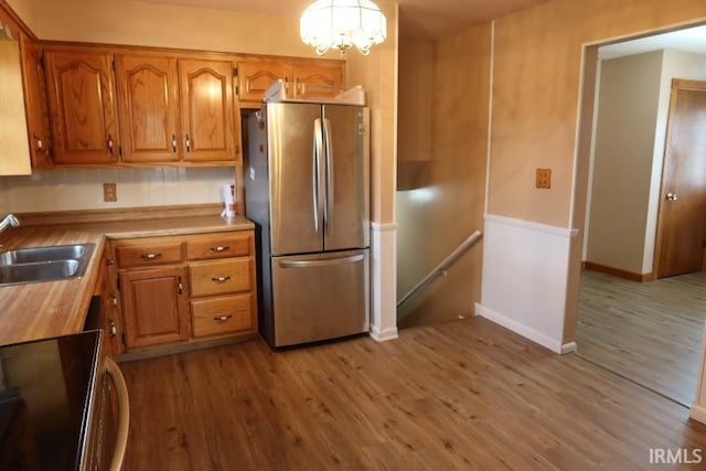 kitchen with sink, light hardwood / wood-style flooring, stainless steel refrigerator, and range