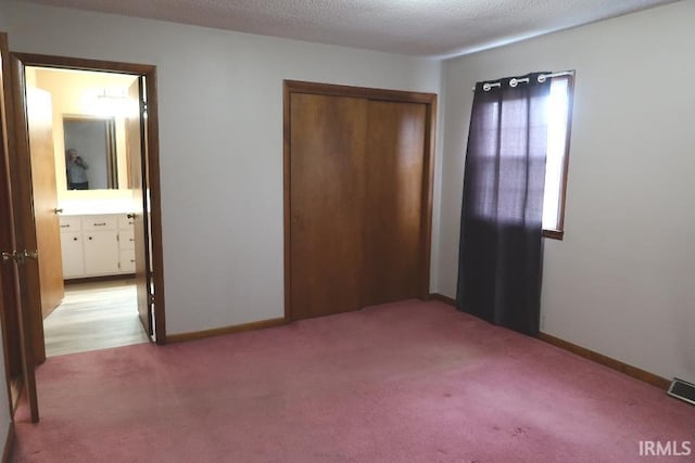 unfurnished bedroom featuring light carpet, a closet, and a textured ceiling