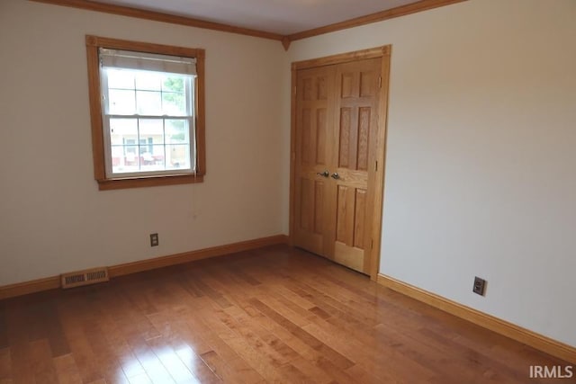 spare room featuring ornamental molding and light wood-type flooring